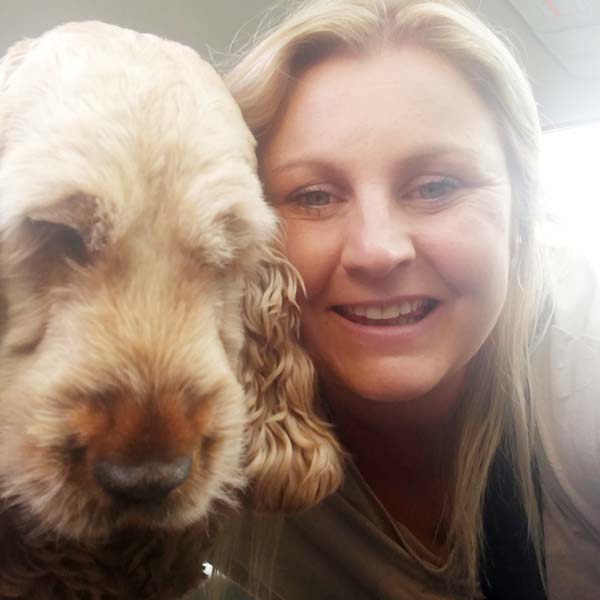 Veterinary Nurse Gemma smiling in a close-up with her Golden Cocker Spaniel, Frankie.